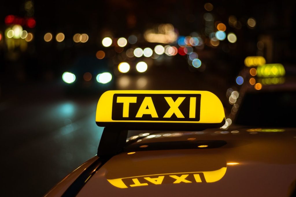 Panneau de taxi lumineux sur une voiture la nuit à Paris, illustrant la mobilité urbaine et le choix entre taxi et VTC en 2025.